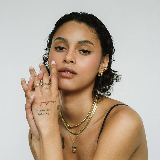 Woman with jewelry and tattoos against a white background