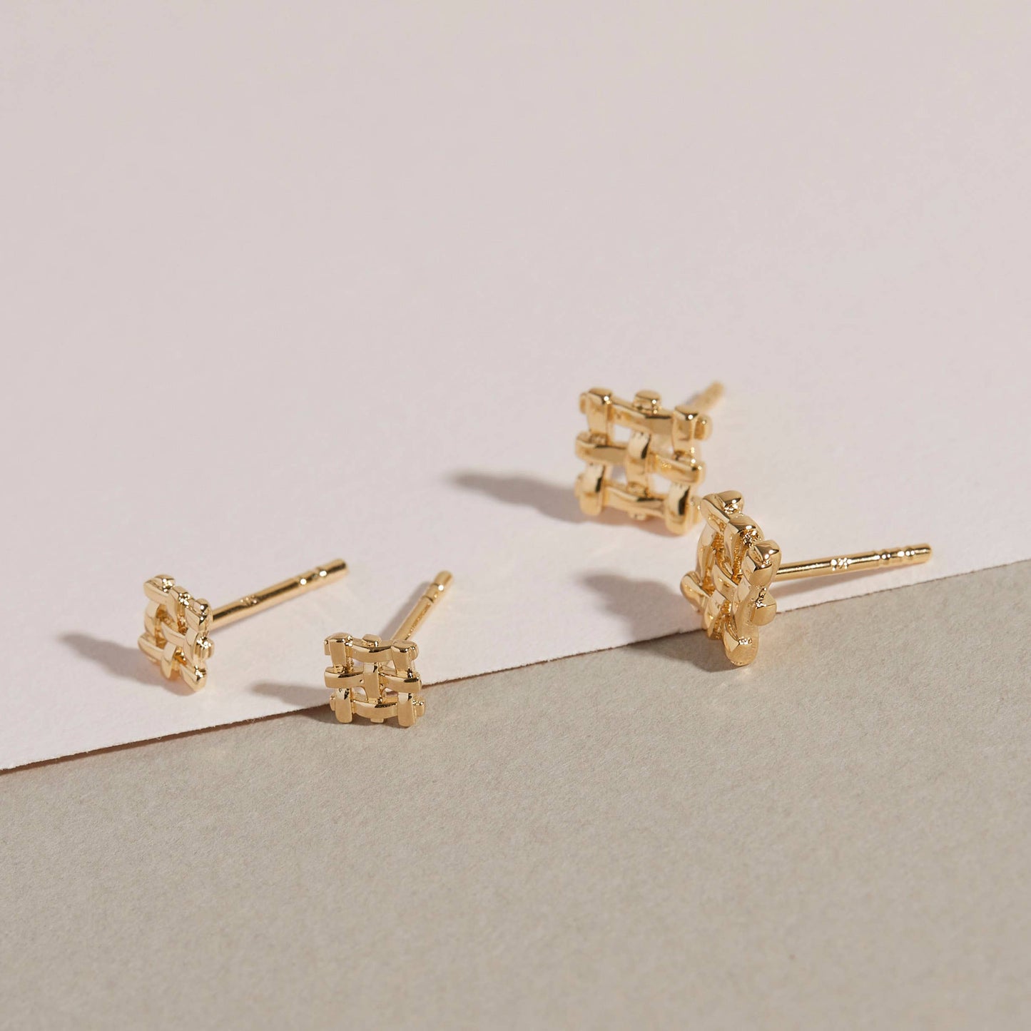 angled view of the mini and small crosshatch studs on a beige background