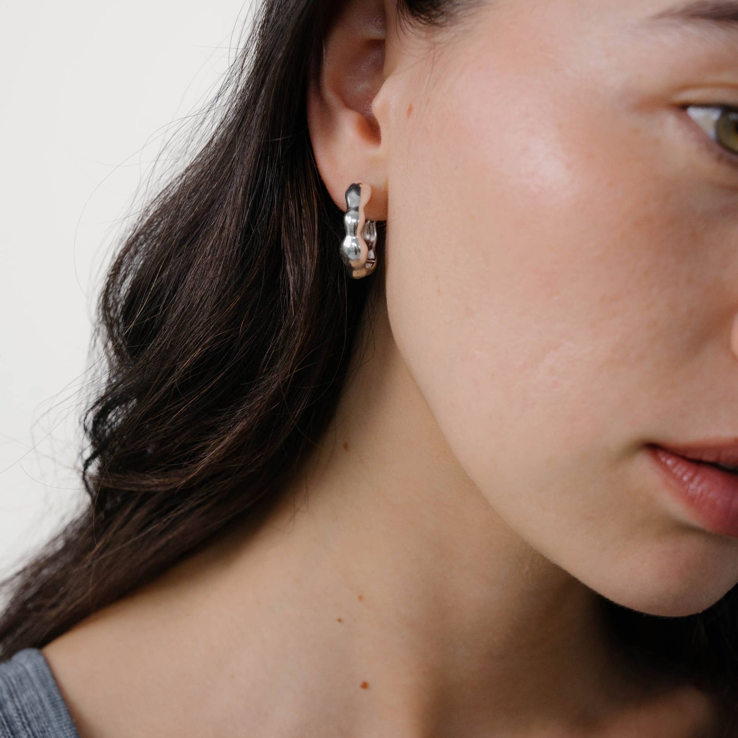 Close-up of a woman wearing earrings with a neutral background