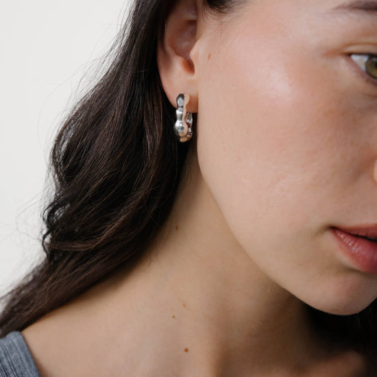 Close-up of a woman wearing earrings with a neutral background