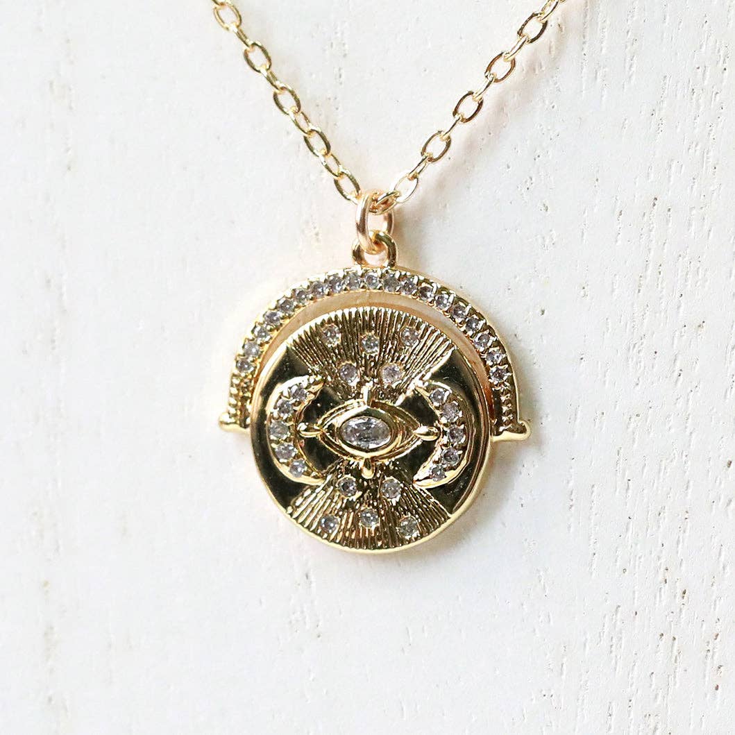 Gold necklace with a circular pendant on a white background