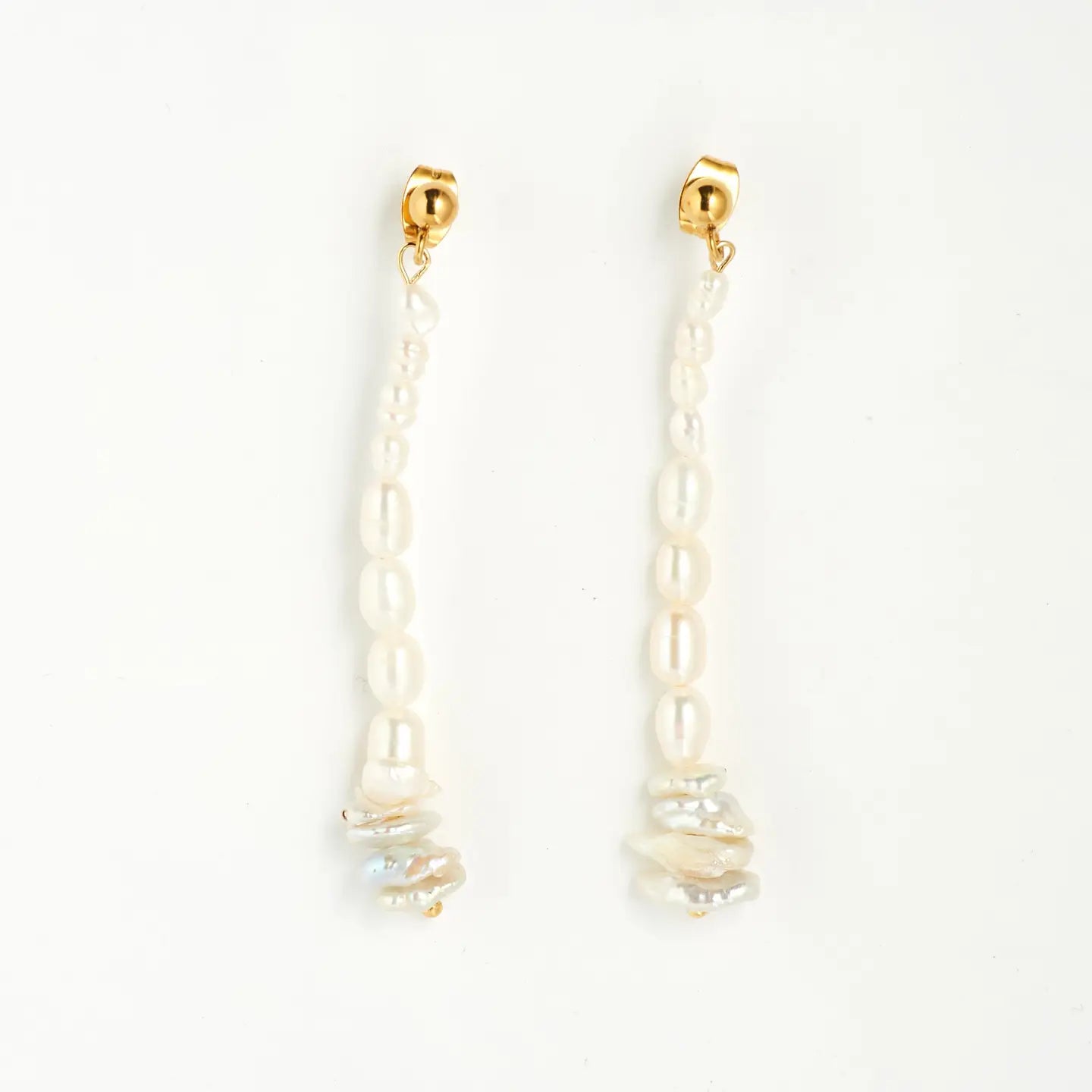 a pair of dangle earrings with varying sized and shaped pearls and gold ball studs on a white background