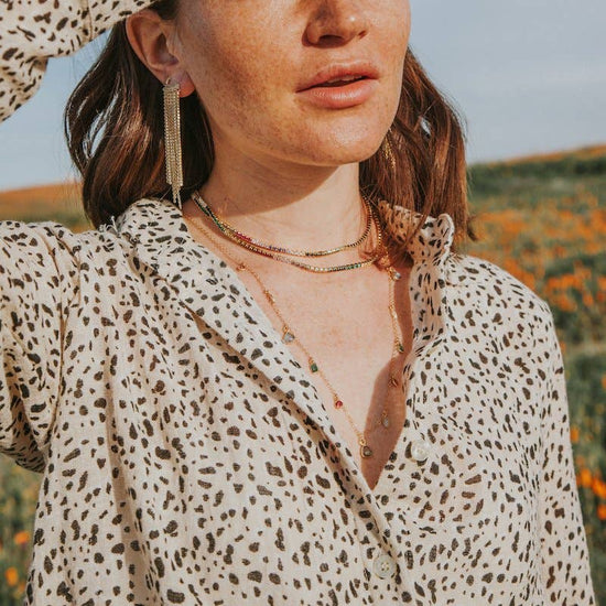 Woman in a leopard print shirt standing outdoors with a clear sky and blurred natural background