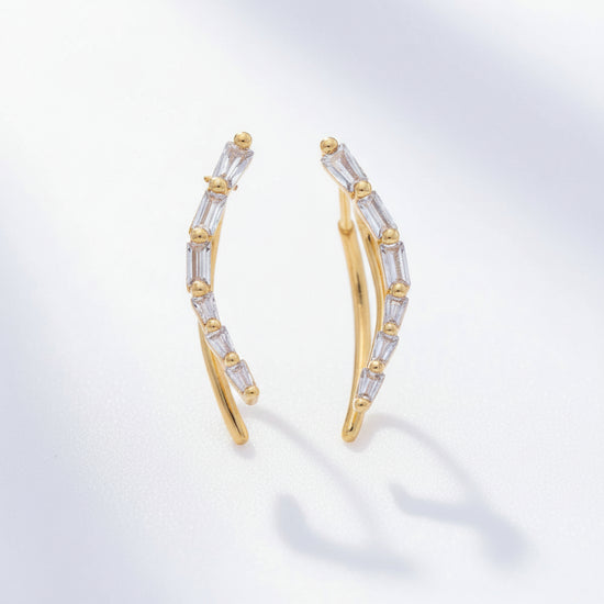 Gold and silver earrings on a light gray background