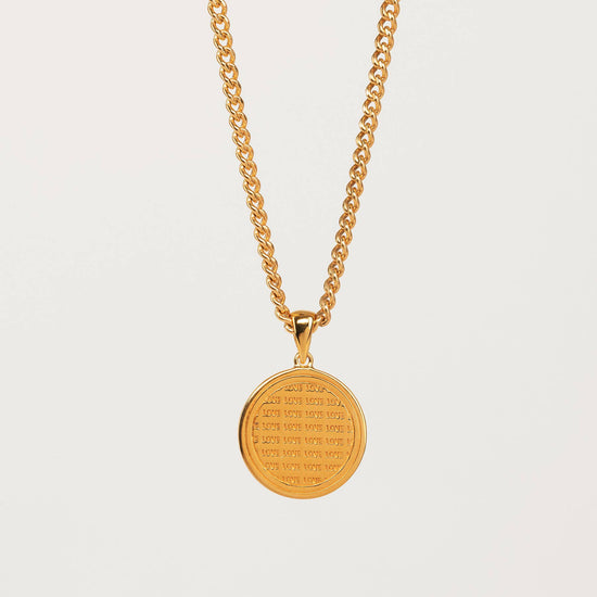 gold coin pendant necklace with love engraving on a grey background