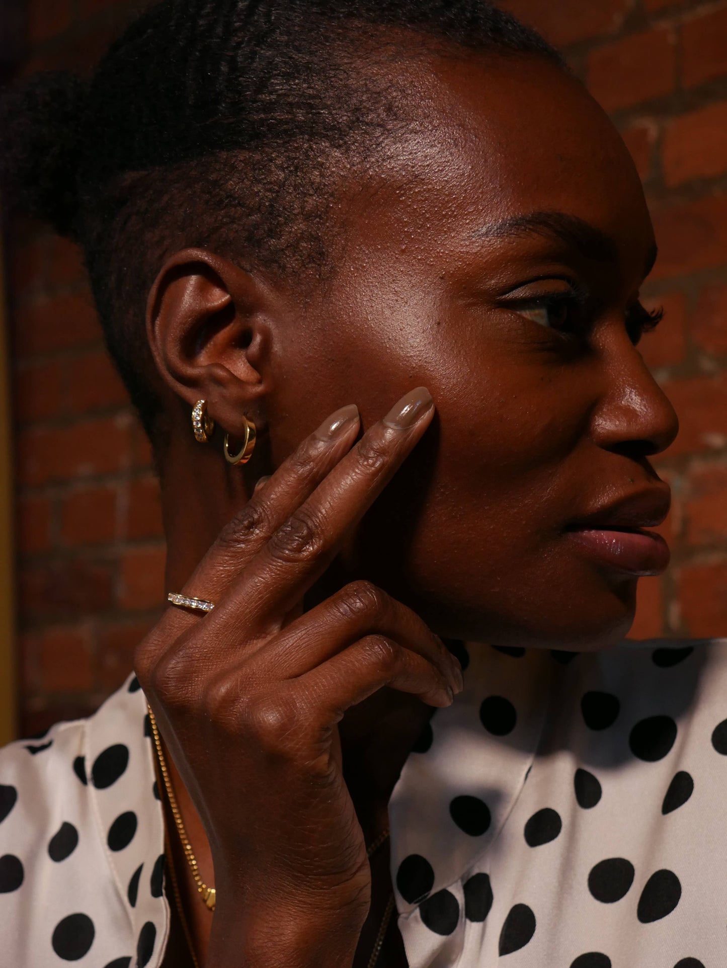 close up of a model wearing the gold huggie hoops