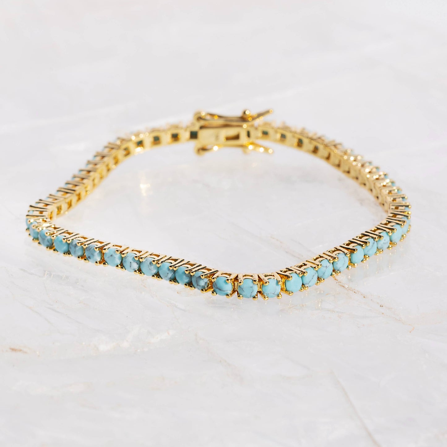 Gold bracelet with turquoise stones on a white background