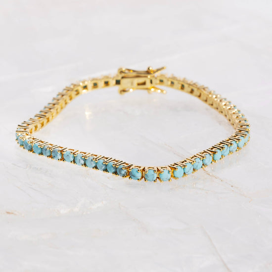 Gold bracelet with turquoise stones on a white background