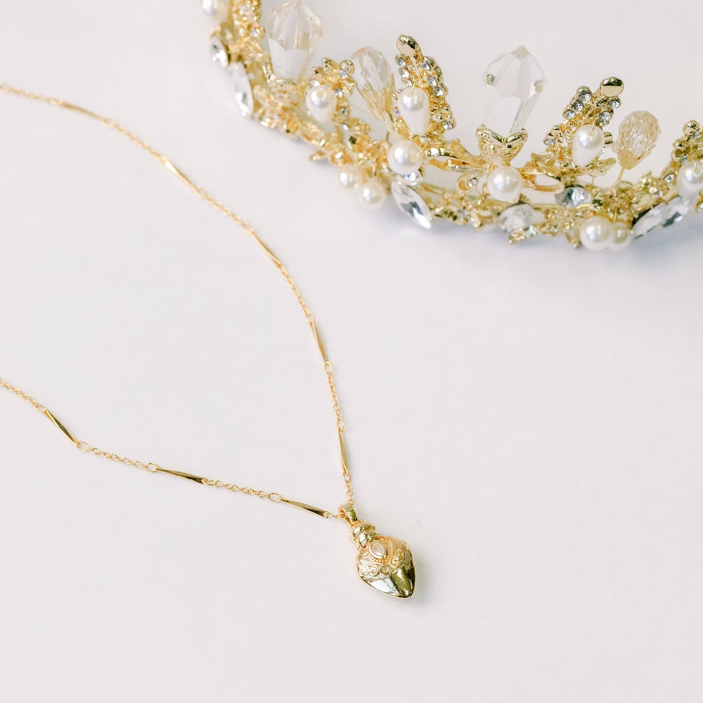 Gold necklace and tiara with pearls on a light background