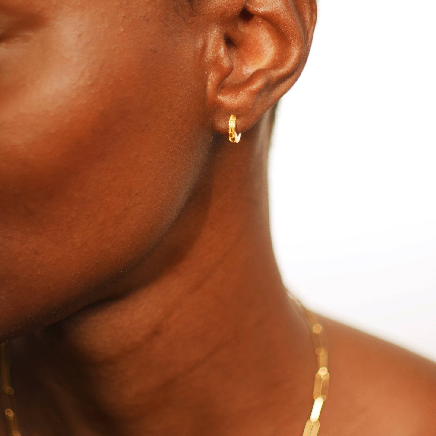 close up of a model wearing the woven huggie earrings