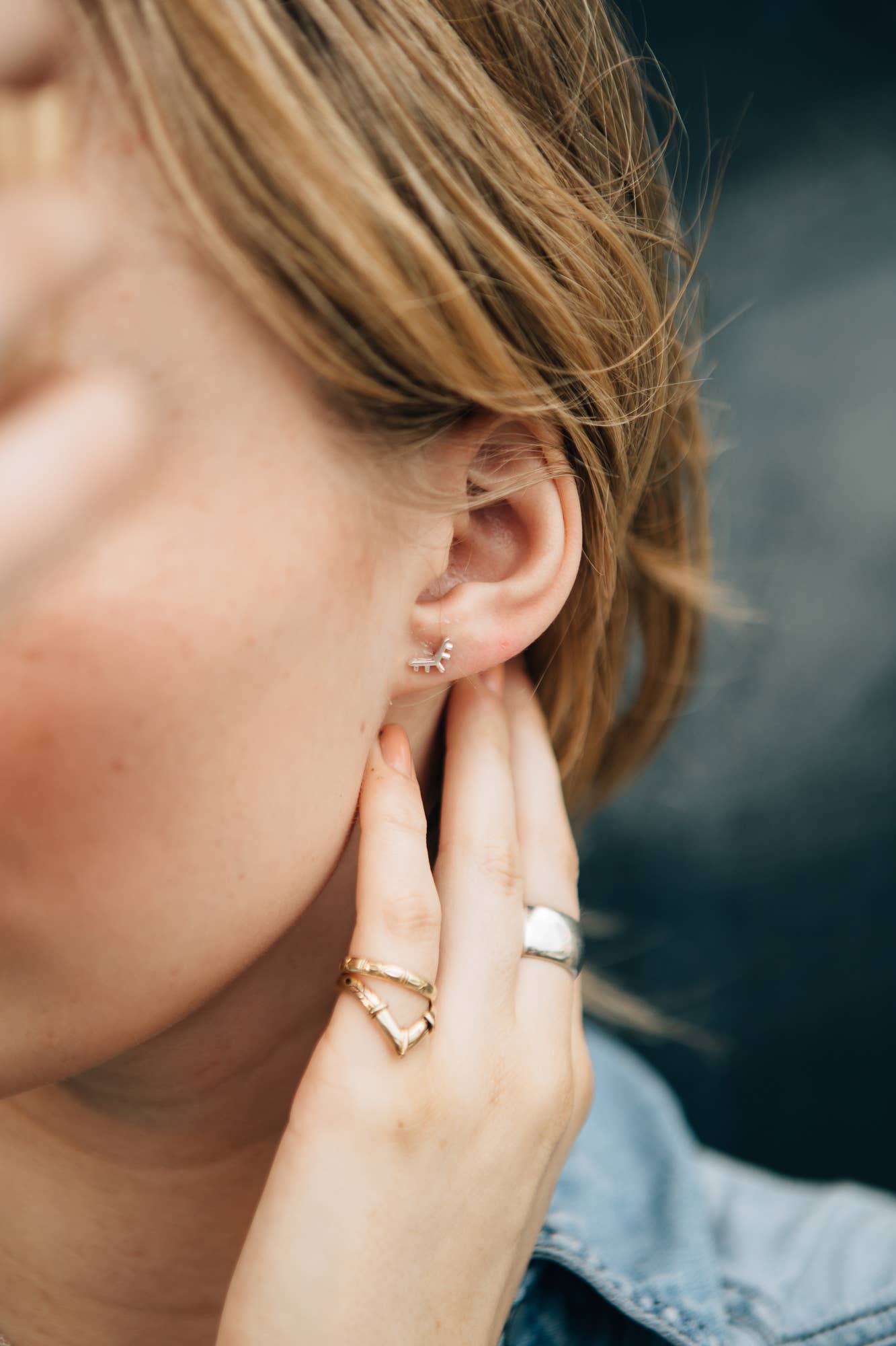 Close-up of a person wearing gold earrings and rings with a blurred background