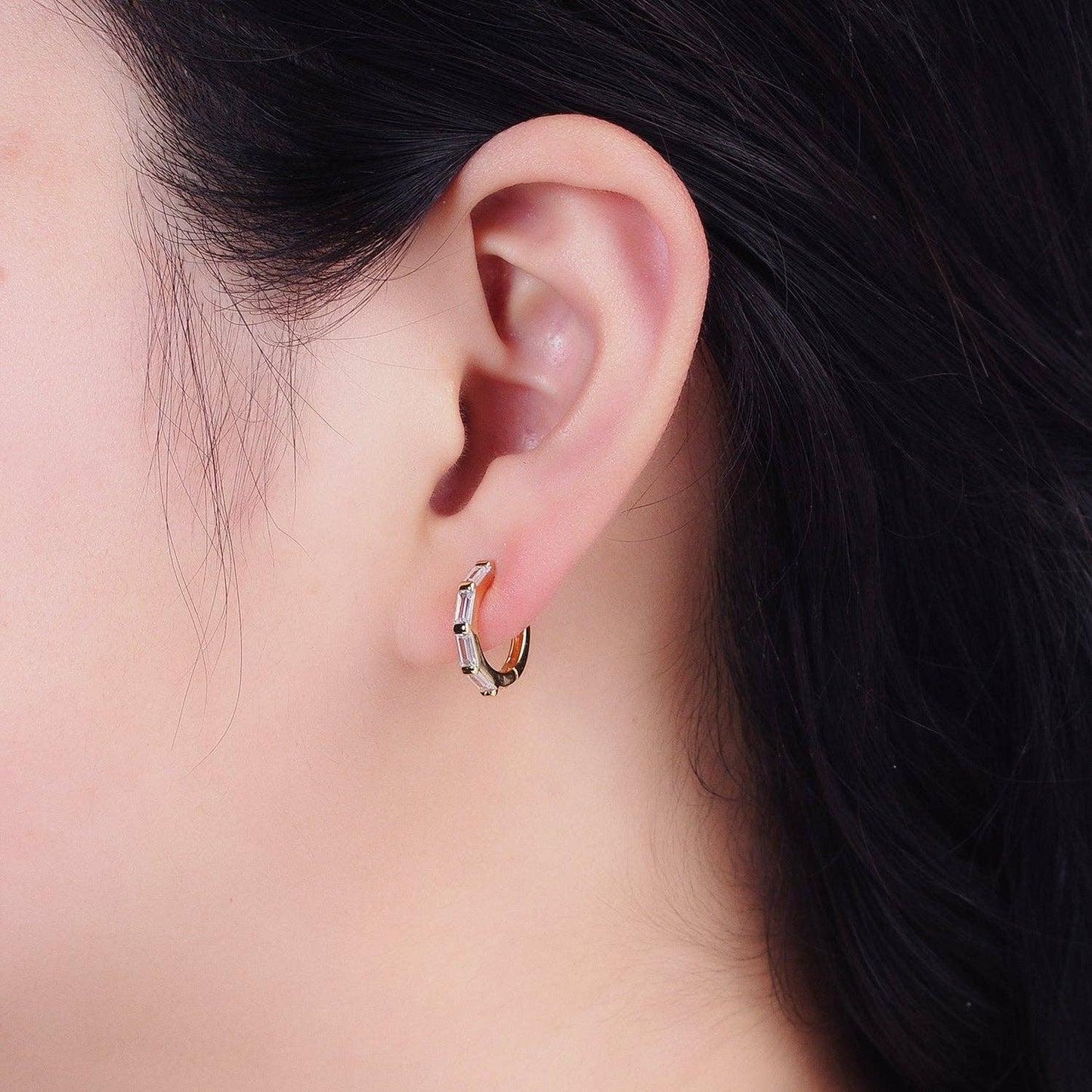 Close-up of an ear wearing a small hoop earring with a blurred background