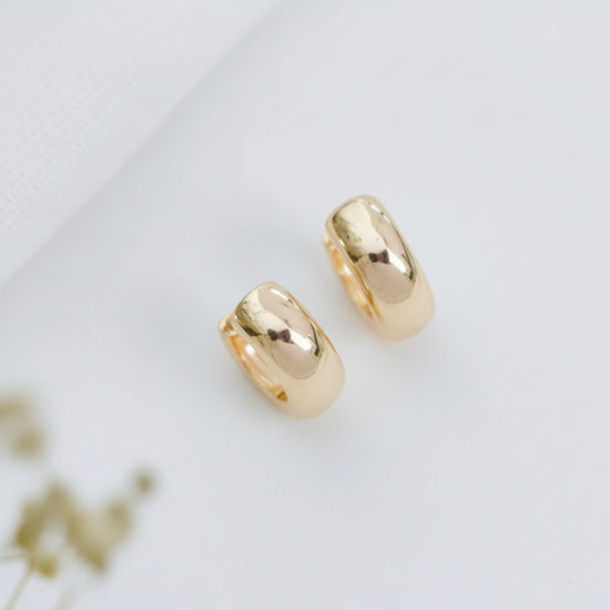 Gold hoop earrings on a white fabric background