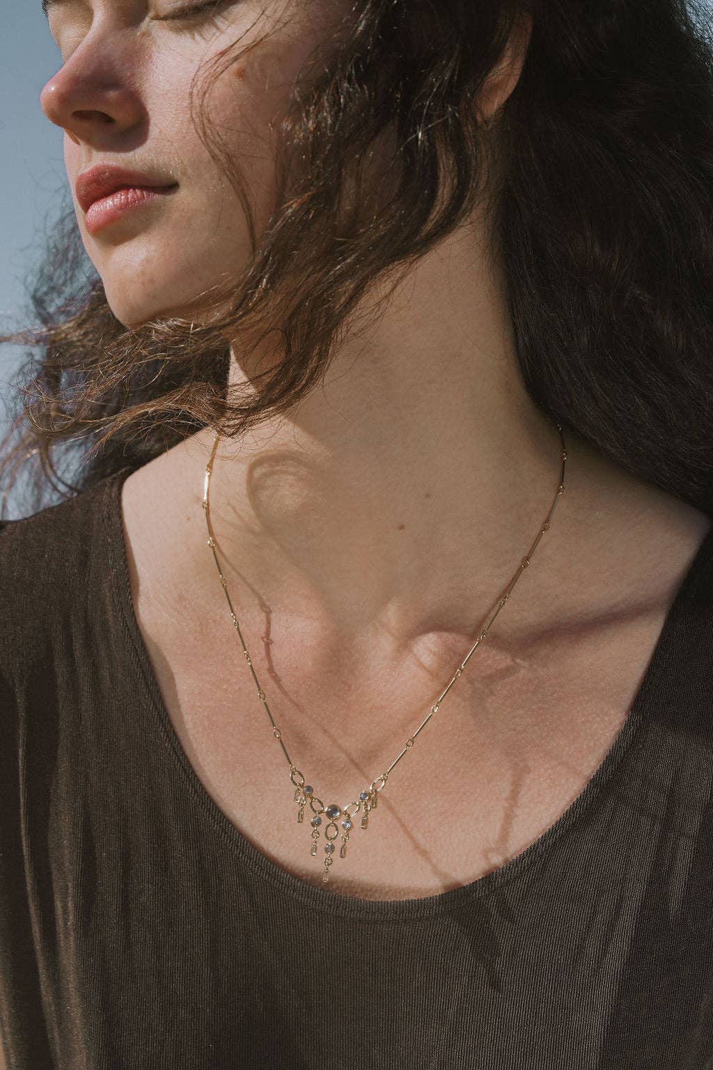 Close-up of a woman wearing a delicate gold necklace with a blurred background