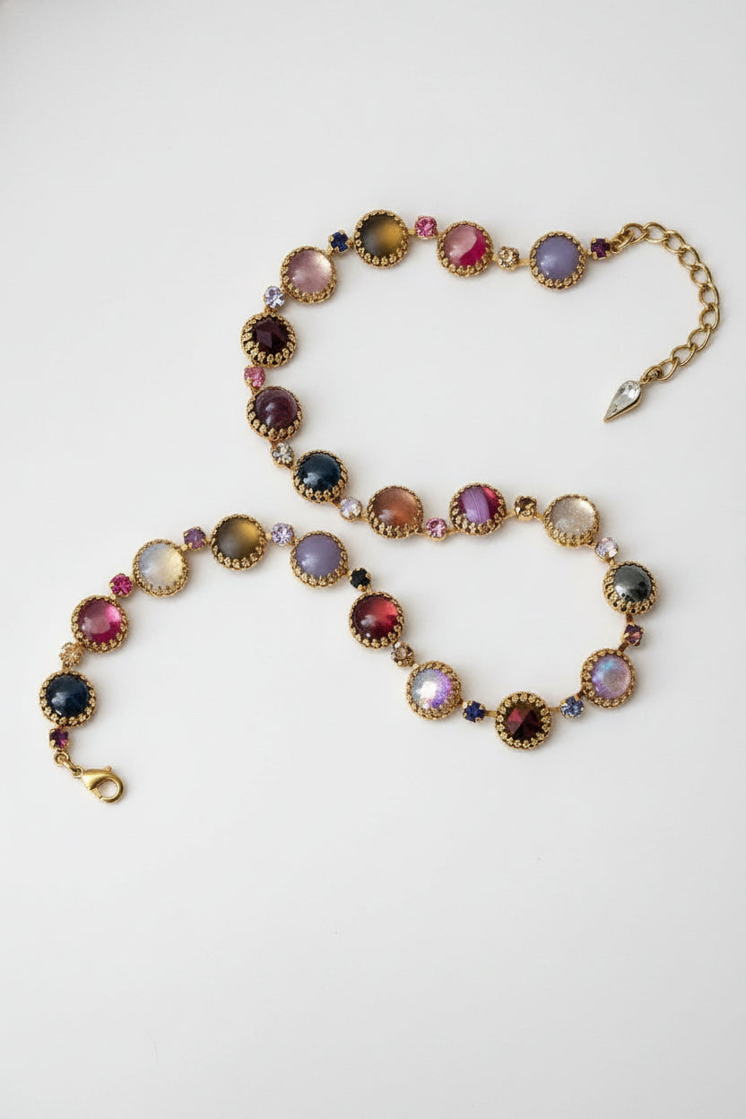 Multicolored gemstone necklace and bracelet on a dark stone surface