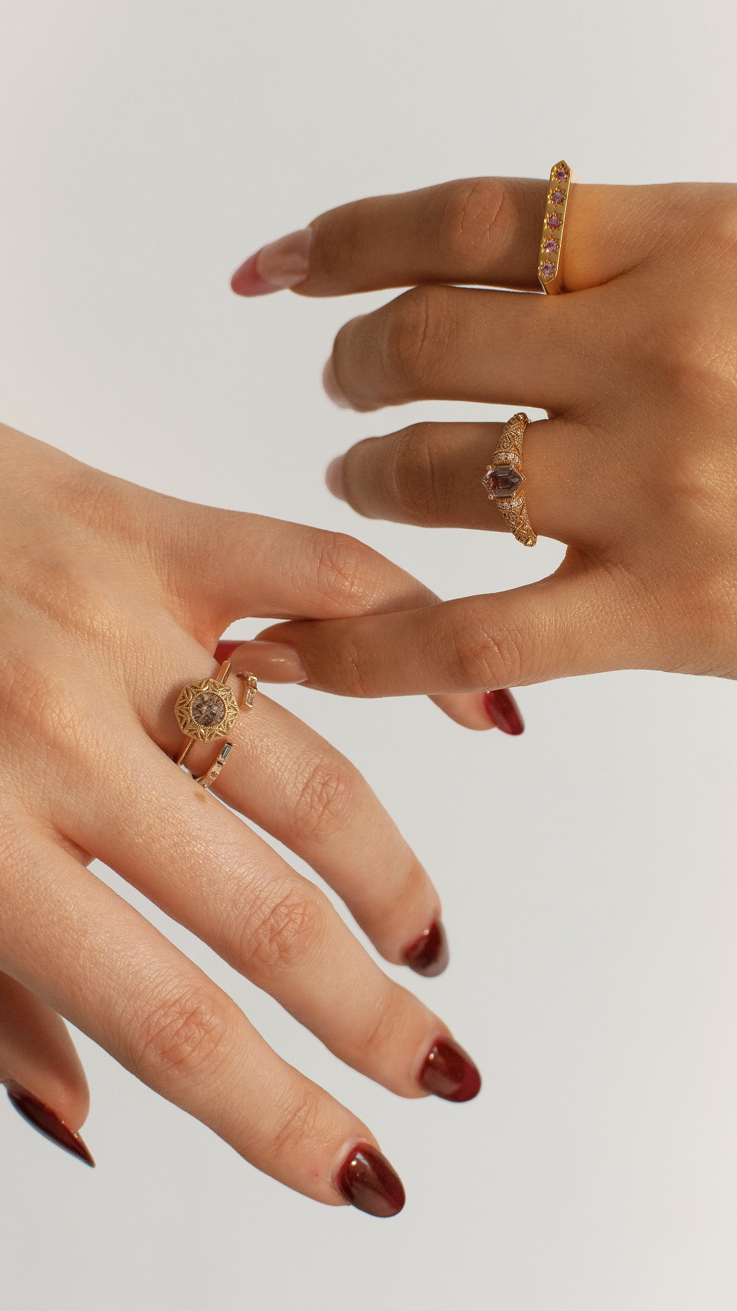 Close-up of two hands wearing gold rings on a light background