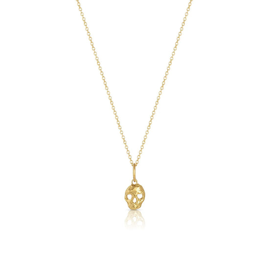 memento mori charm on a thin gold chain on white background