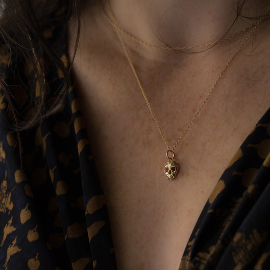 close up of a model wearing the skull memento mori charm on a thin gold chain