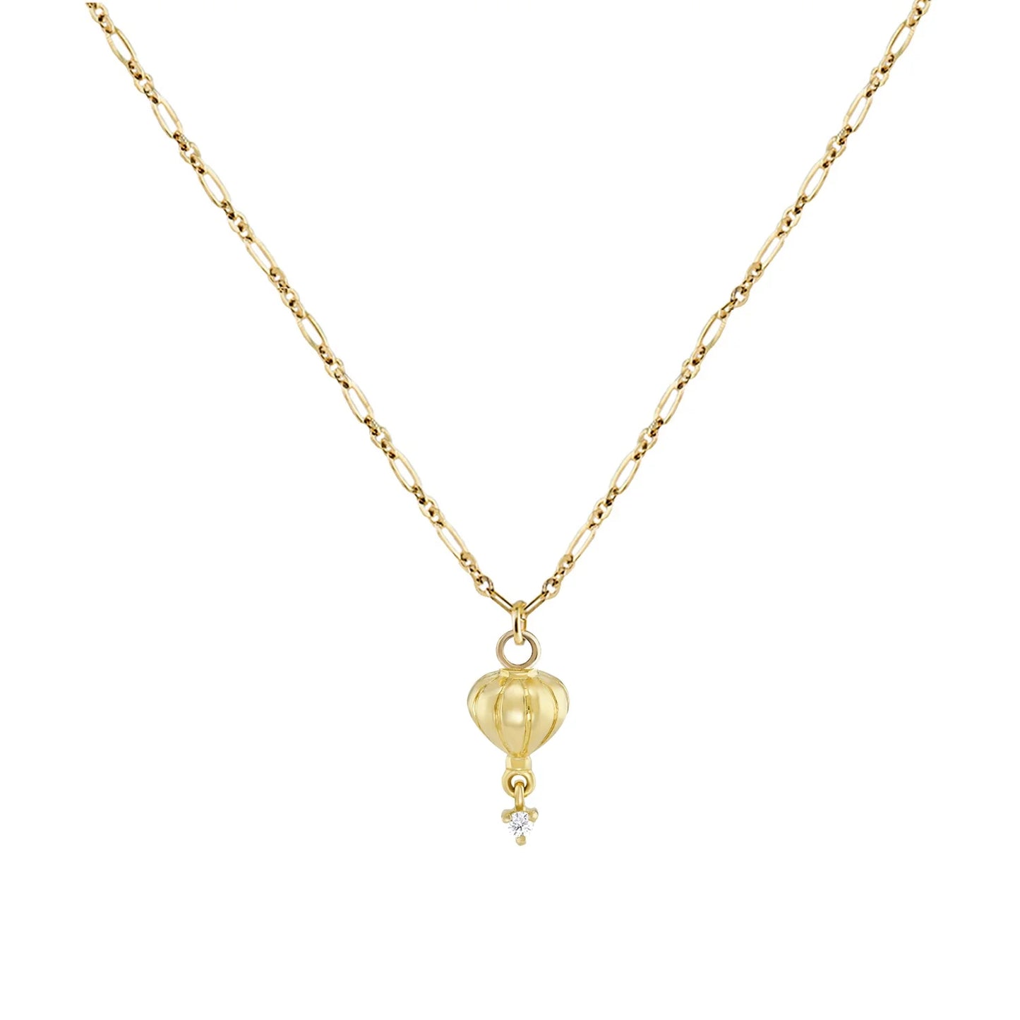 a gold drop pendant with diamond accents and a figaro chain on a white background