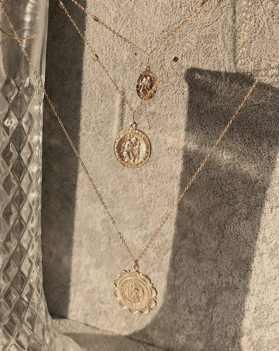 three gold coin pendants dangle on a stone background