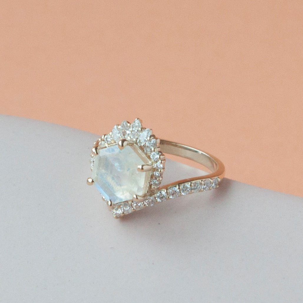 Diagonal view of the moonstone devoir ring on grey and peach background.