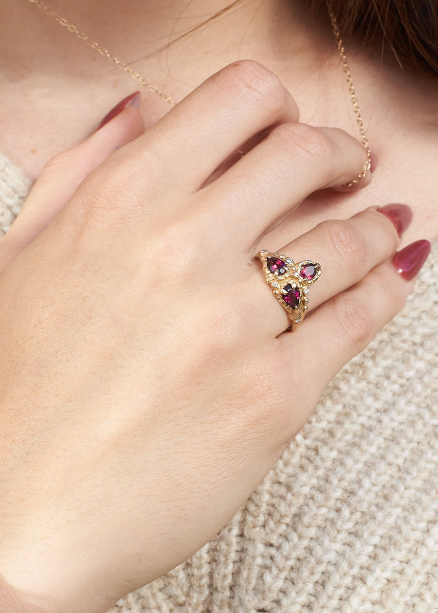 Gold, pear cut diamond ring pictured on someones right hand pressed against their shoulder