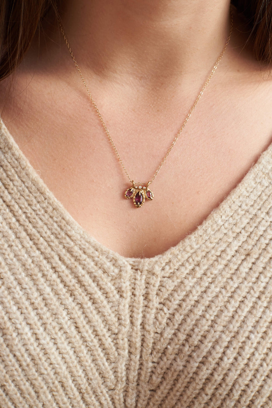 3 purple marquis cut garnets, accompanied by diamonds, on gold chain pictured on persons chest