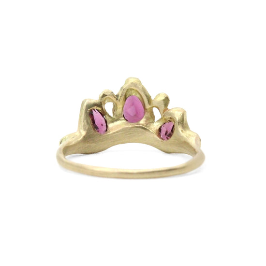 gold ring with 3 rasberry colored garnets, surrounded by smaller diamonds pictured from behind on white background