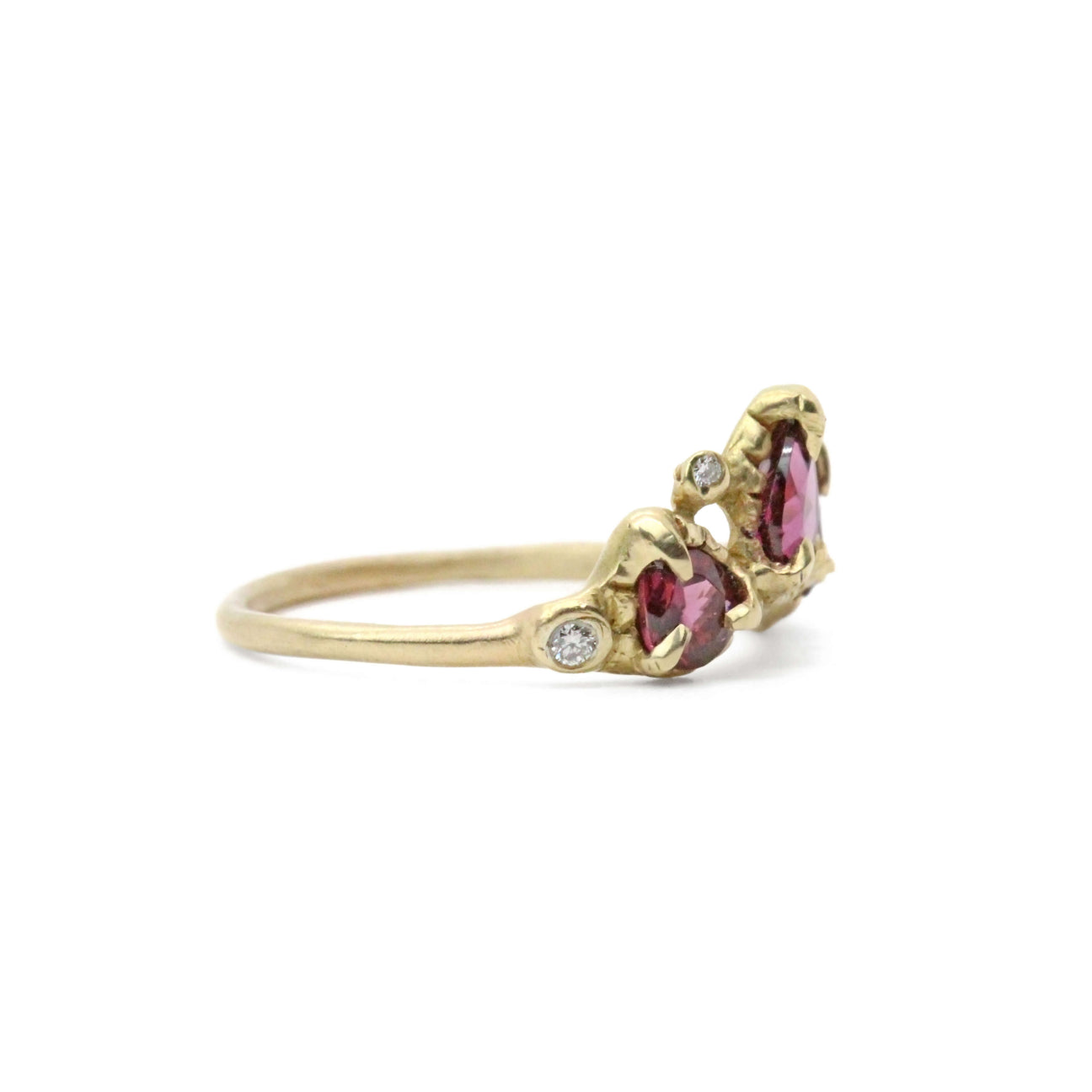 gold ring with 3 rasberry colored garnets, surrounded by smaller diamonds pictured from the side on white background