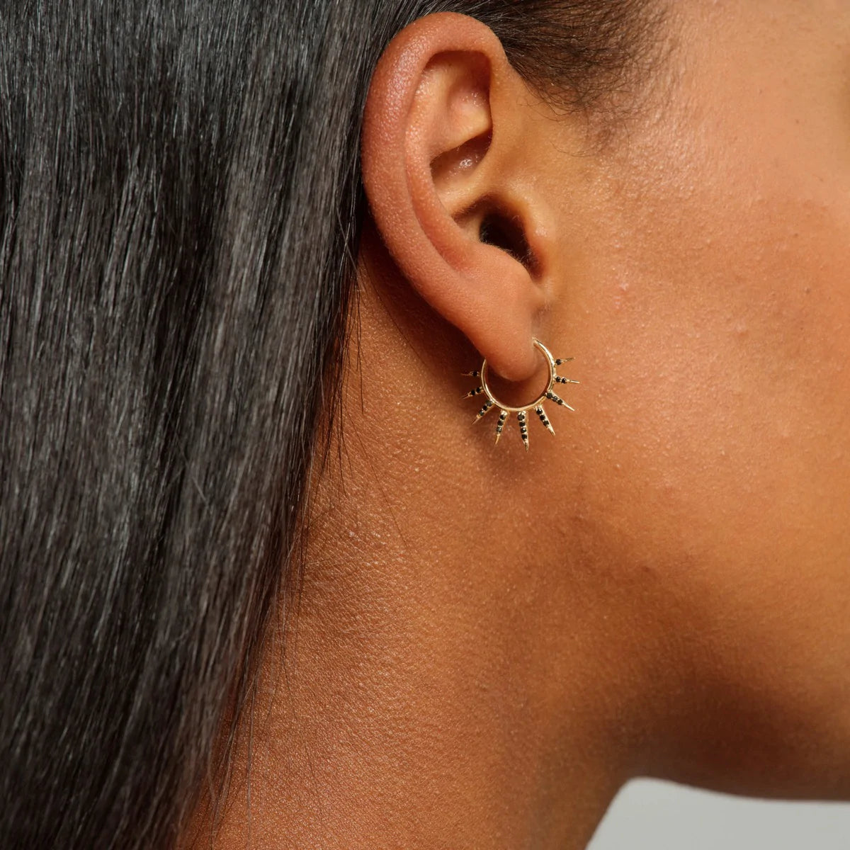 close up of a model wearing the split point hoop with black diamonds
