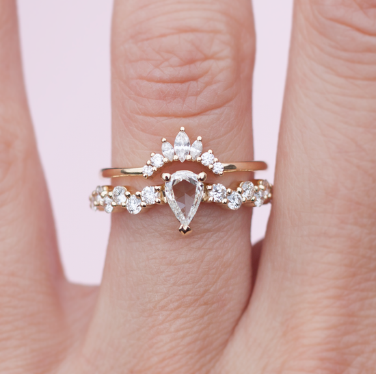 Rose cut pear shaped diamond ring with diamond cluster band, stacked with a diamond crown band, close up on hand.