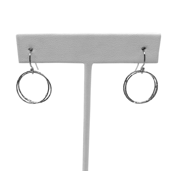Sterling silver triple circle earrings on earring stand with white background.