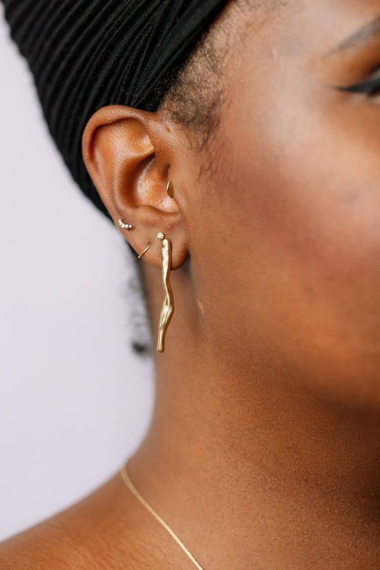 Gold drip stud earrings on model
