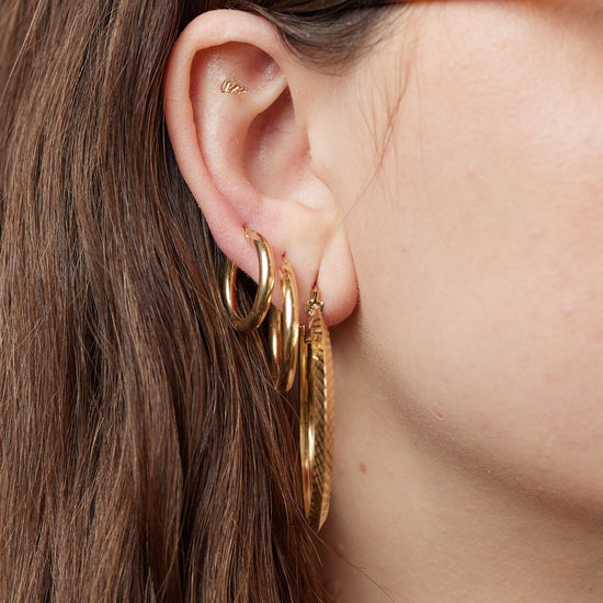Load image into Gallery viewer, Three gold earrings shown on ear
