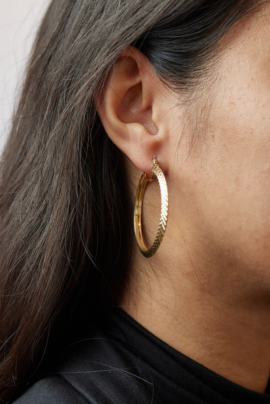 Large gold crosshatch hoops on ear