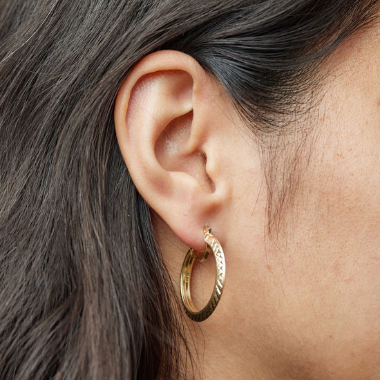 Gold crosshatch small hoops shown on model ear