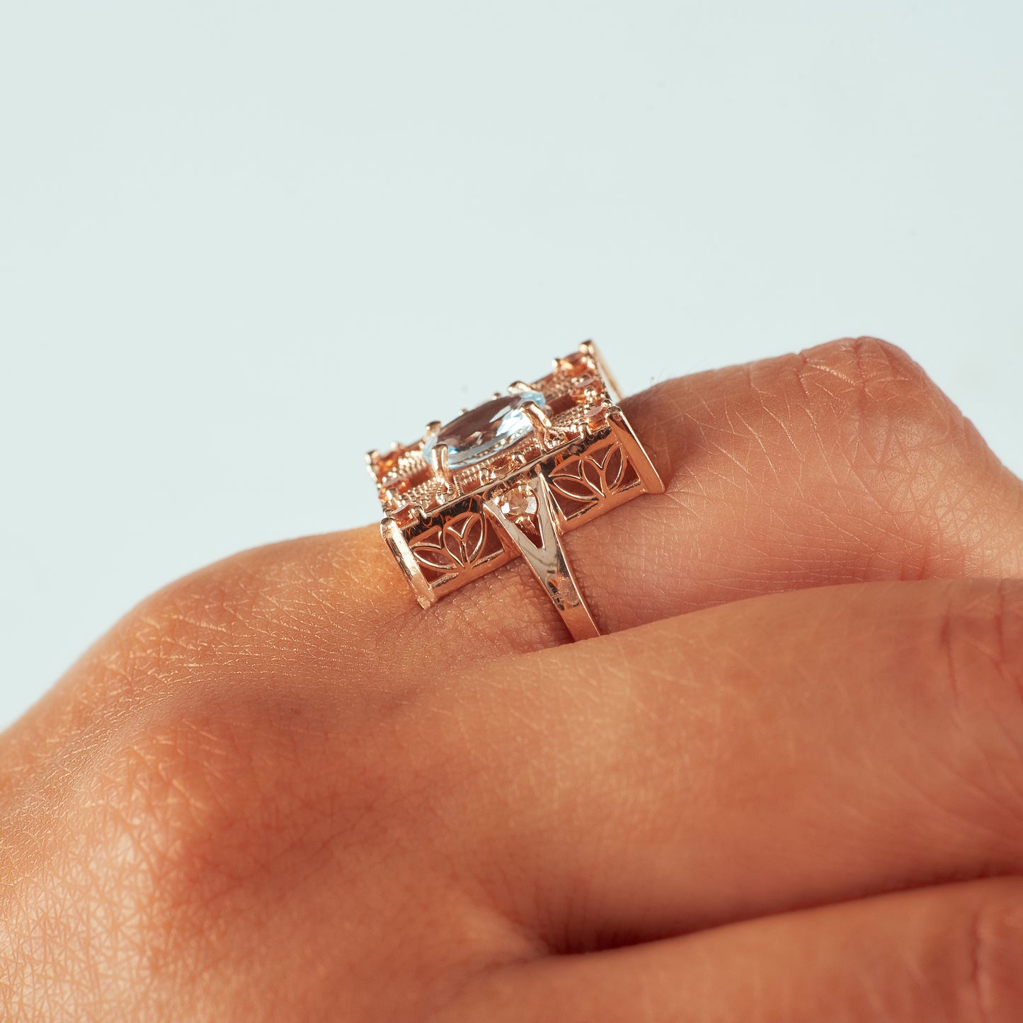 Side view of 14k rose gold aquamarine and champagne diamond ring on hand model.