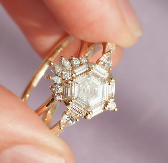Hand holding the hexagon diamond nebula ring close up with diamond crown stacking band.