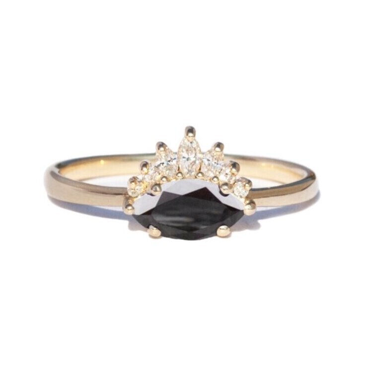 Sideways set black diamond marquise with white diamond crown ring, on white background.