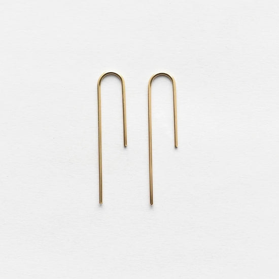 gold asymmetrical arch threader earrings on white background