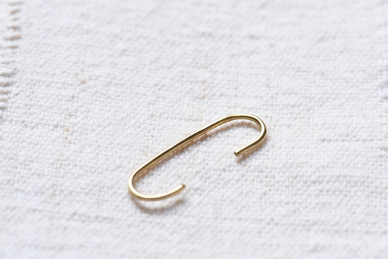 elongated gold cuff earring on light taupe linen background