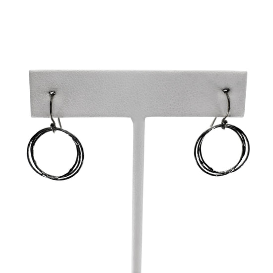 Oxidized sterling silver triple circle earrings on earring stand with white background.