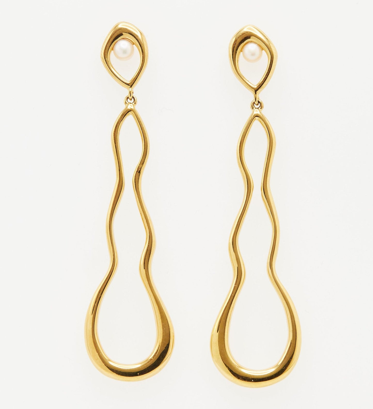 elongated squiggle outline gold earrings with small pearl accent on white background