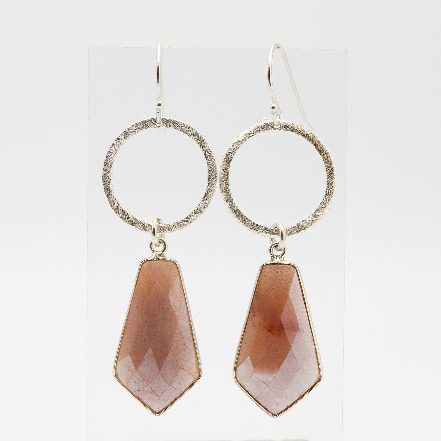 silver open circle earrings with geometric peach moonstone drop on white background