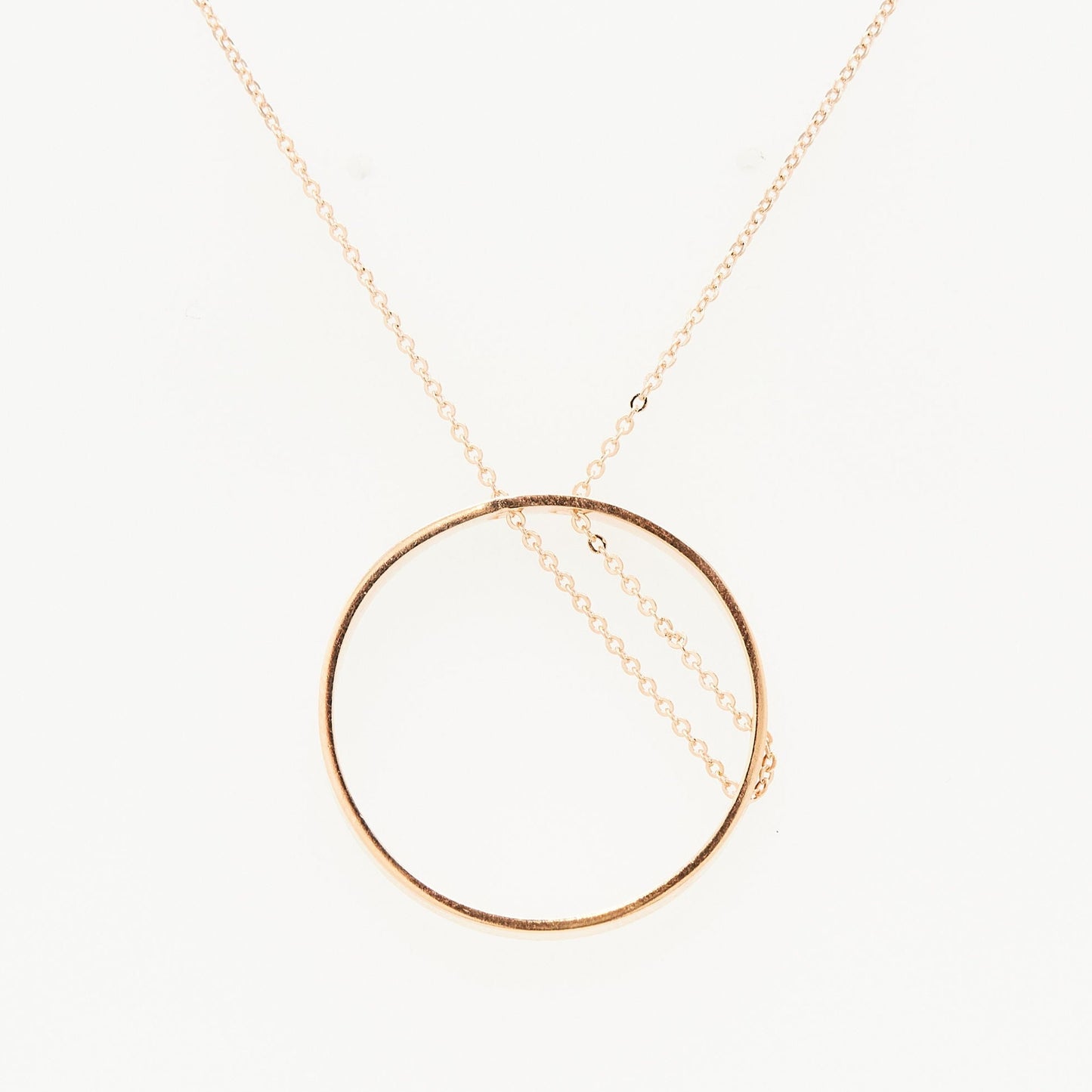 rose gold open circle necklace with chain threaded through on white background