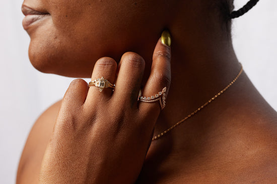 Load image into Gallery viewer, close up of model wearing the double v band on pointer finger and two diamond rings on ring finger, with hand on her face
