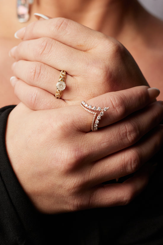 close up of models hands, wearing the double v diamond band on her pointer finger and a diamond solitaire ring on her ring finger