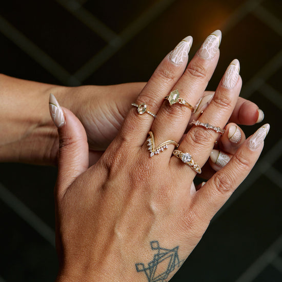 Load image into Gallery viewer, a model wearing the crystal tourmaline ring on her right pointer finger with two diamond rings on her middle finger and two diamond rings on her ring finger, with a black tile background
