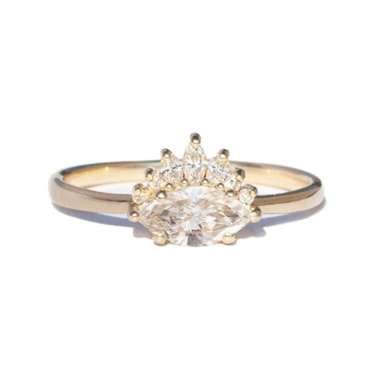 White diamond sideways set marquise gold ring with diamond crown, on white background.