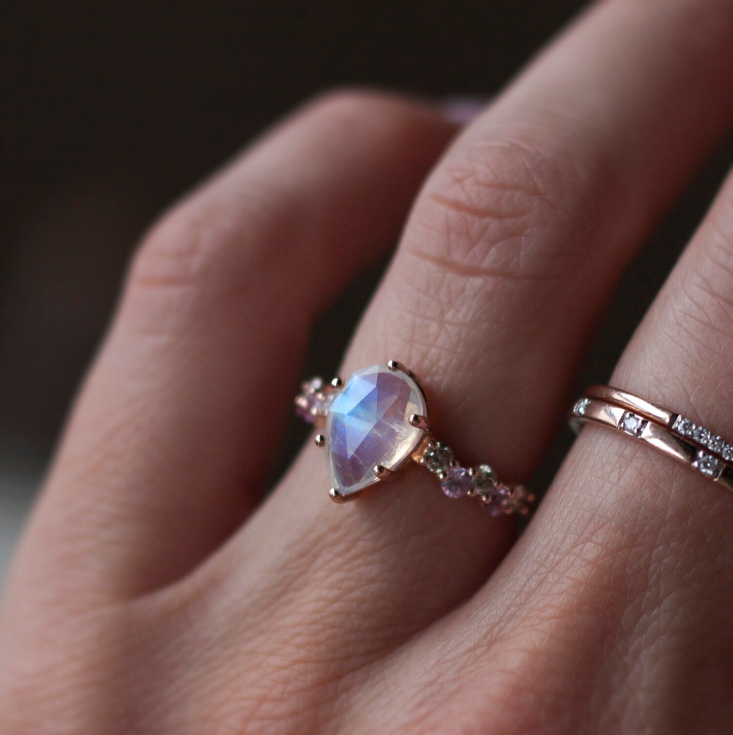 Load image into Gallery viewer, Hand modeling pear shaped rainbow moonstone intertwine ring and two diamond stacking bands.
